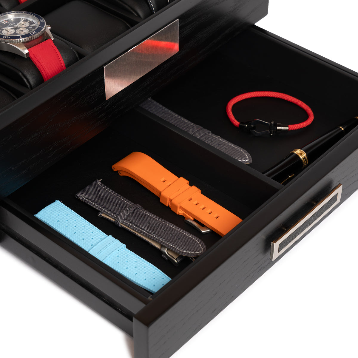 Accessory drawer of the Kennett 10 slot black wooden watch box holding spare watch straps, a rope bracelet and a pen
